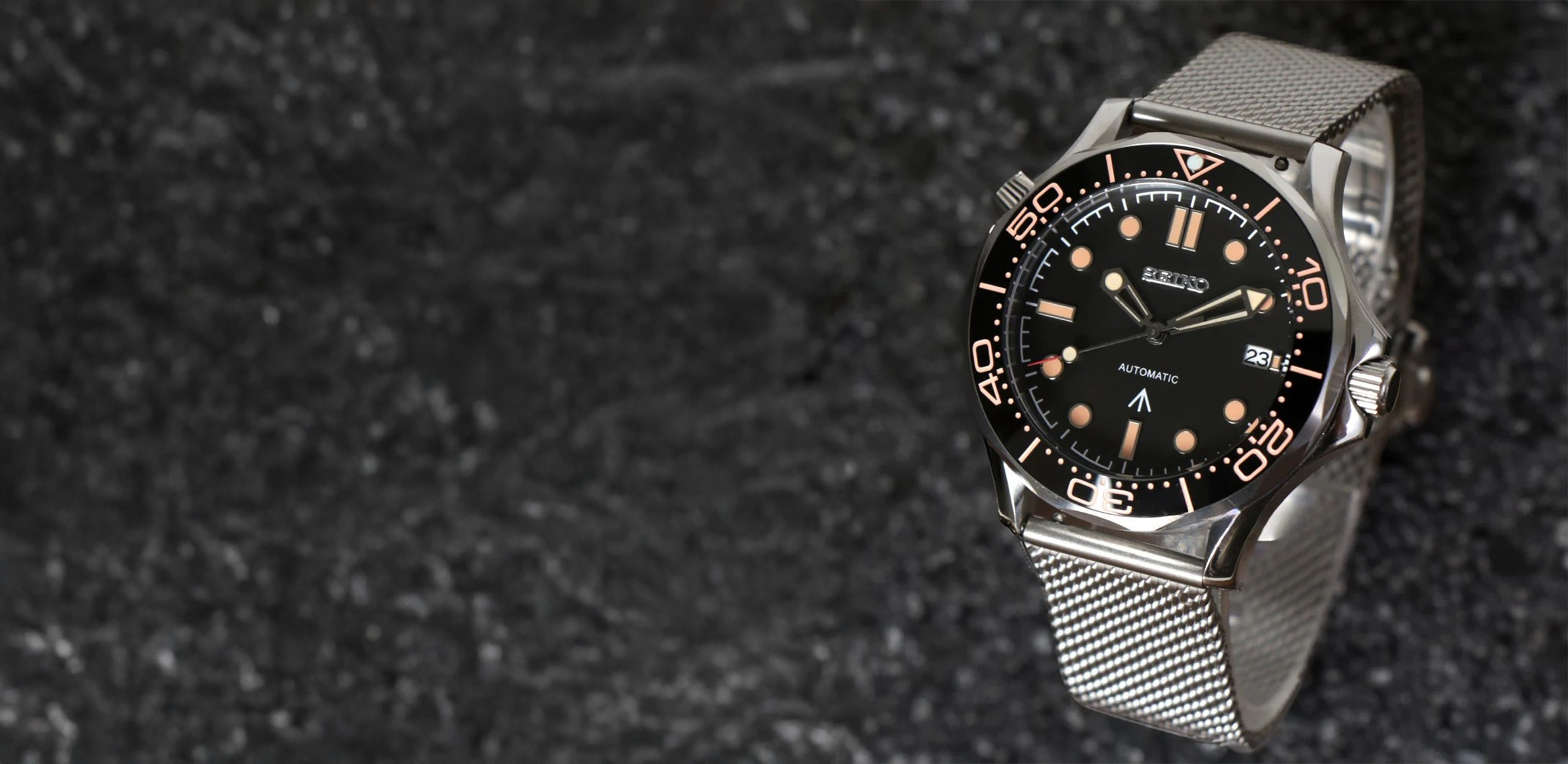 Silver automatic watch with a black dial, showing date and time.