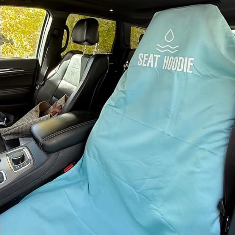 A light blue 'Seat Hoodie' car seat cover is shown on the driver's seat inside a vehicle.