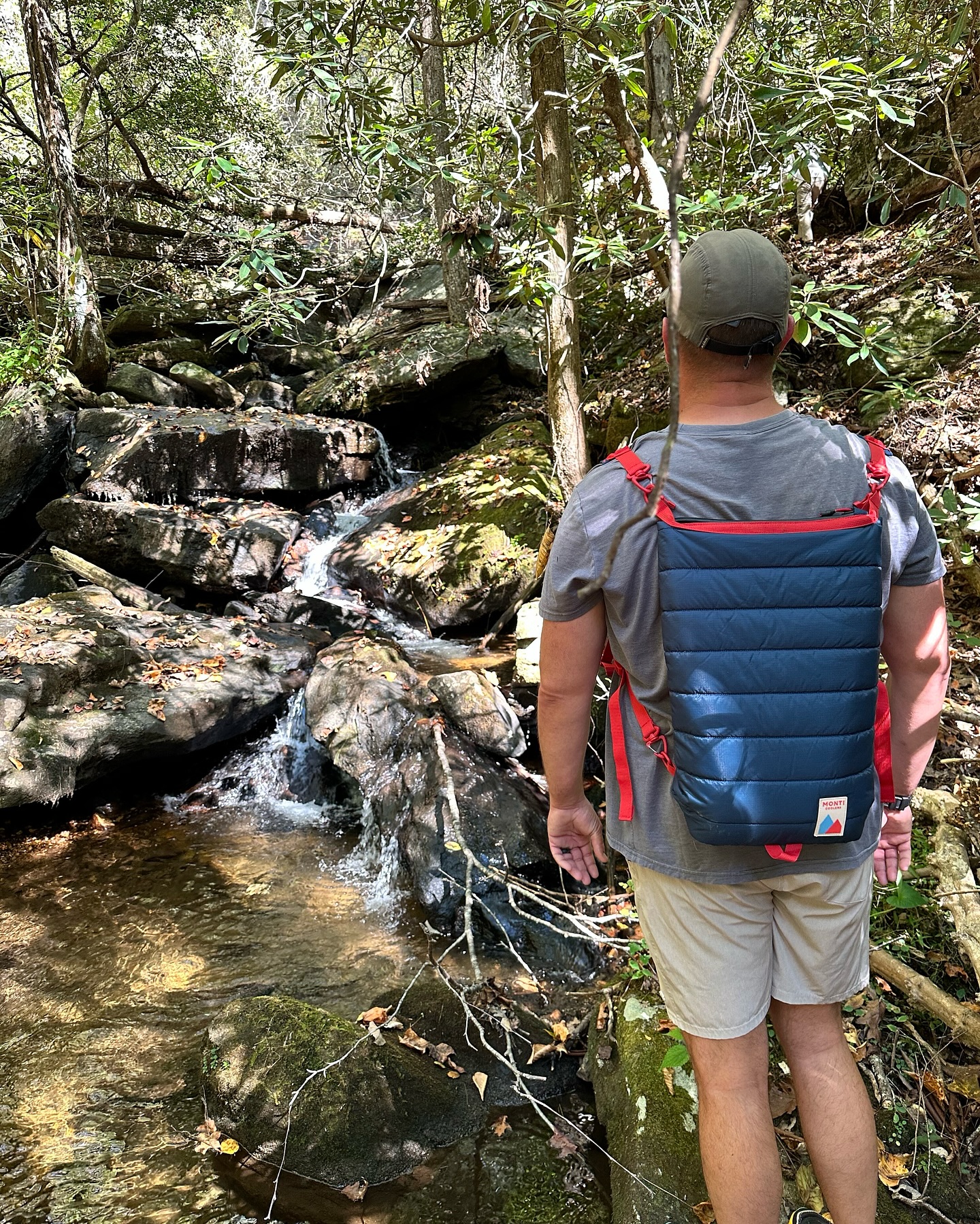 Person drinking with dog in desert landscape with red rock formations.