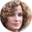 A headshot of a person with curly hair and a neutral expression.