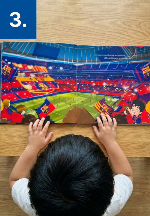 An overhead view of a child with dark hair reading a picture book of a soccer stadium.