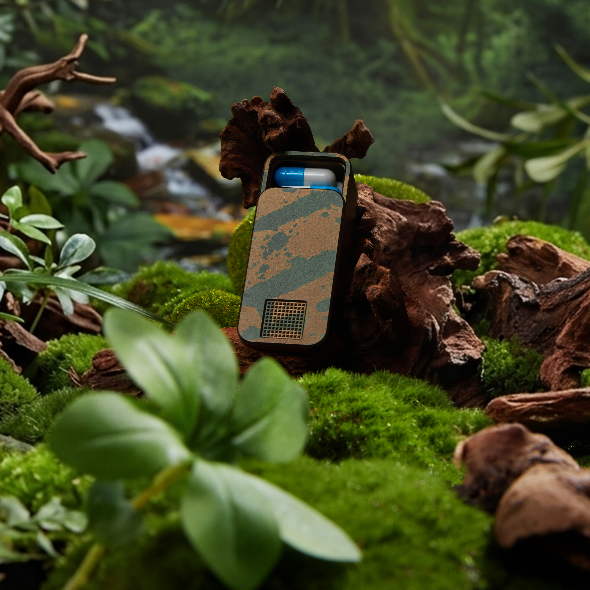 A camouflaged container holding a blue and white pill sits on a mossy, wooded surface.