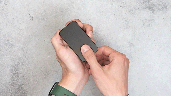 Hands holding a small black rectangular device against a gray background.