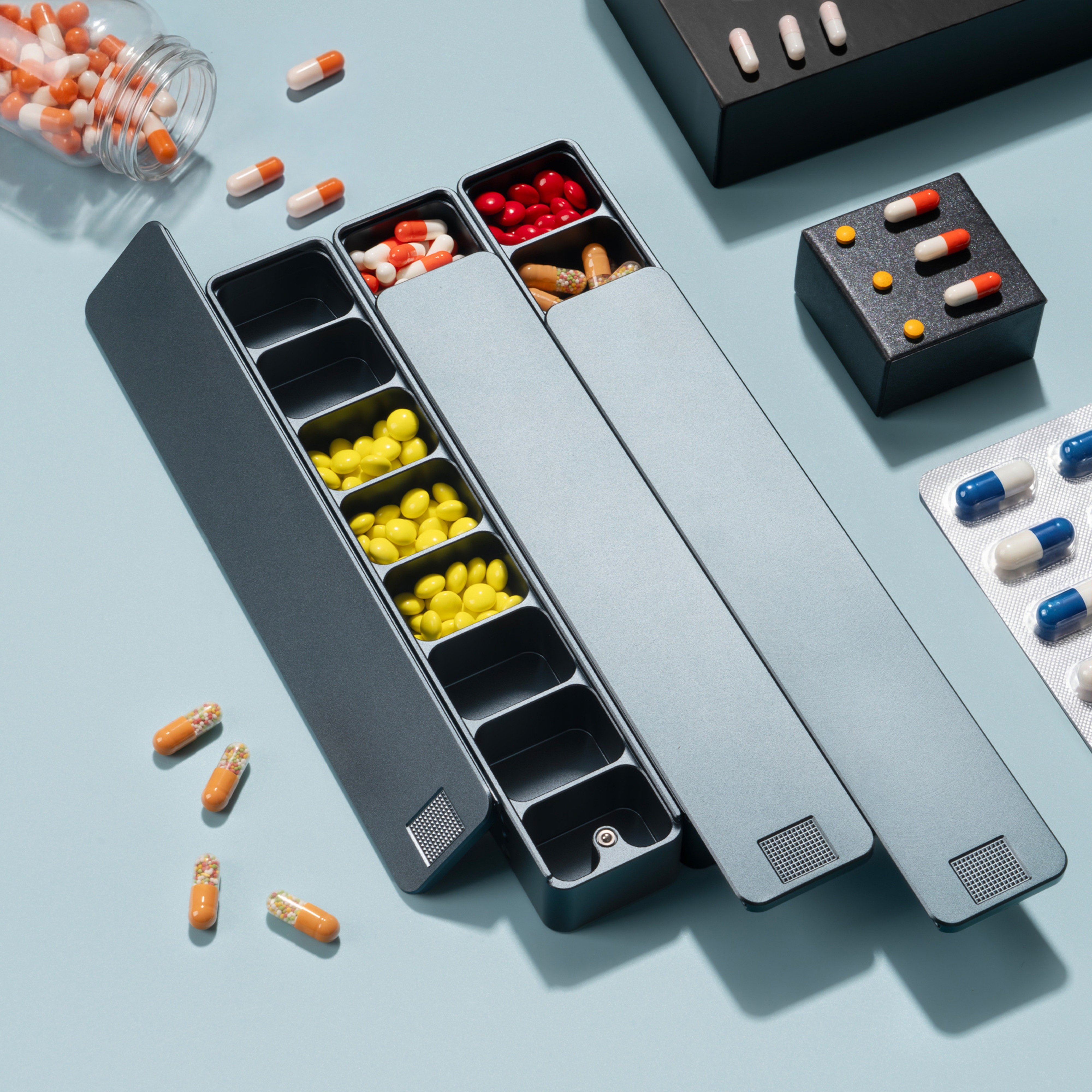 Pill organizers with various colorful pills and capsules arranged on a light blue surface.