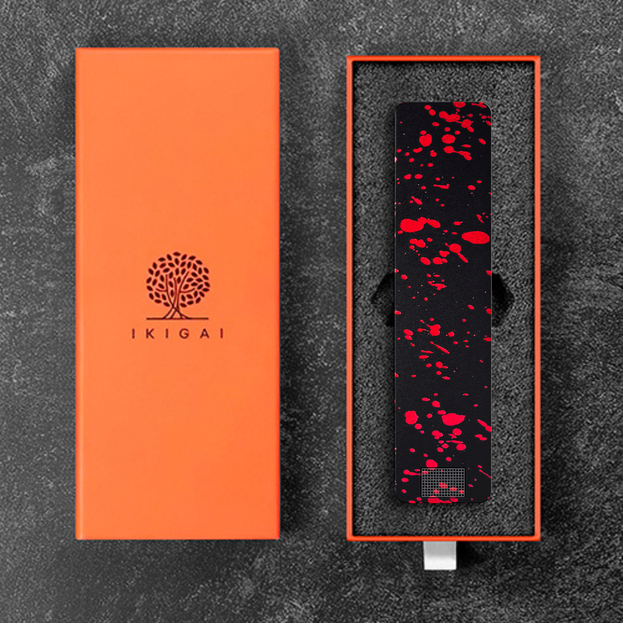 An orange box with an Ikigai logo next to a black electronic device with red splatters in its case.