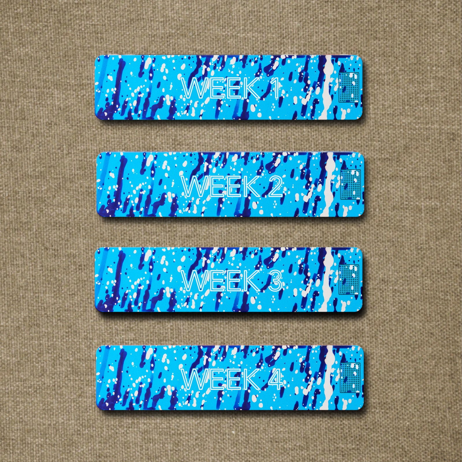 Four blue, paint-splattered rectangular labels on a brown textured background, labeled Week 1, Week 2, Week 3, and Week 4.