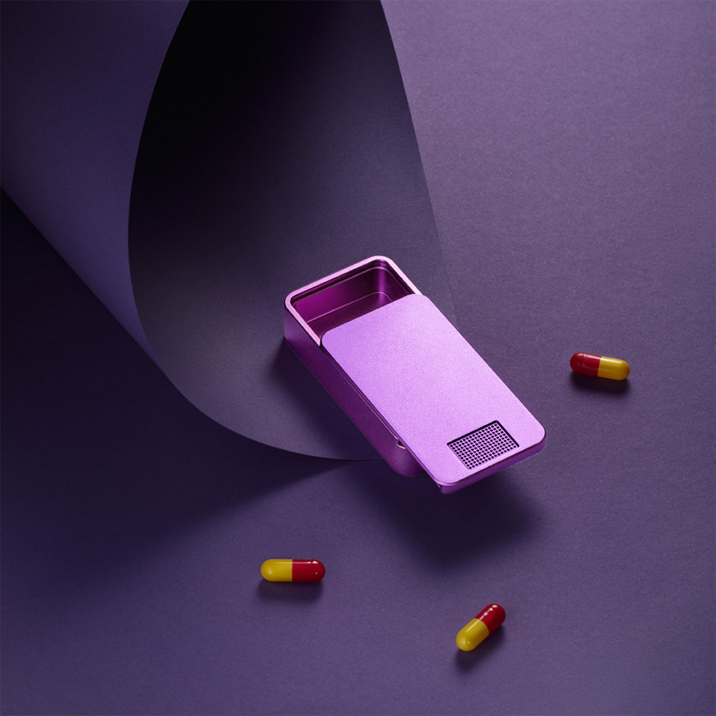 Purple metallic object with red and yellow capsules on purple background.