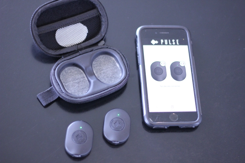 Two devices, a phone displaying app, and an open case on a dark surface.