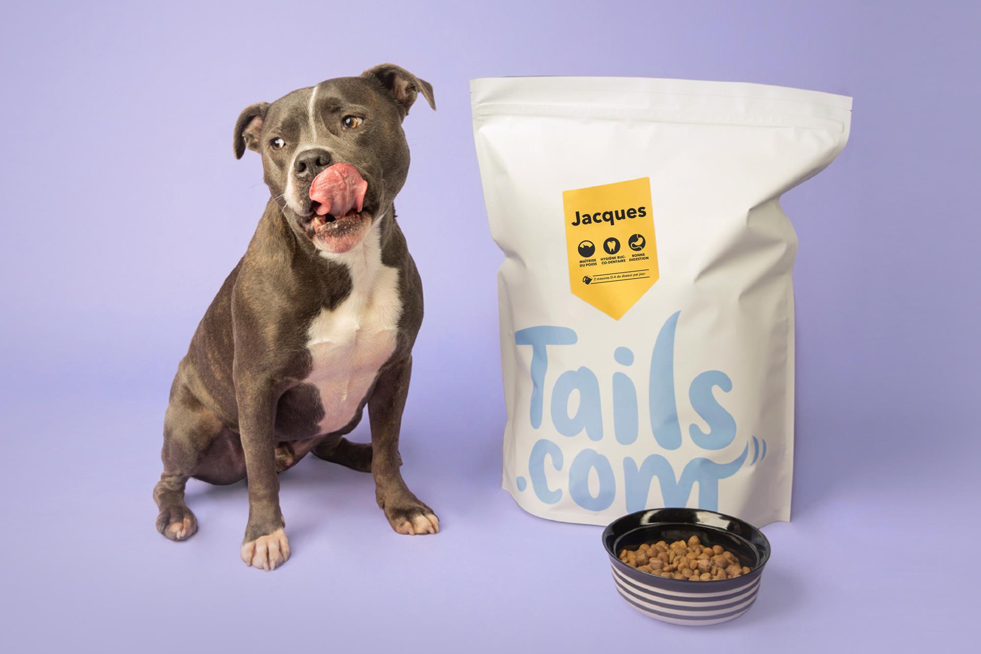 Dog licking lips next to a bag of dog food and a bowl.