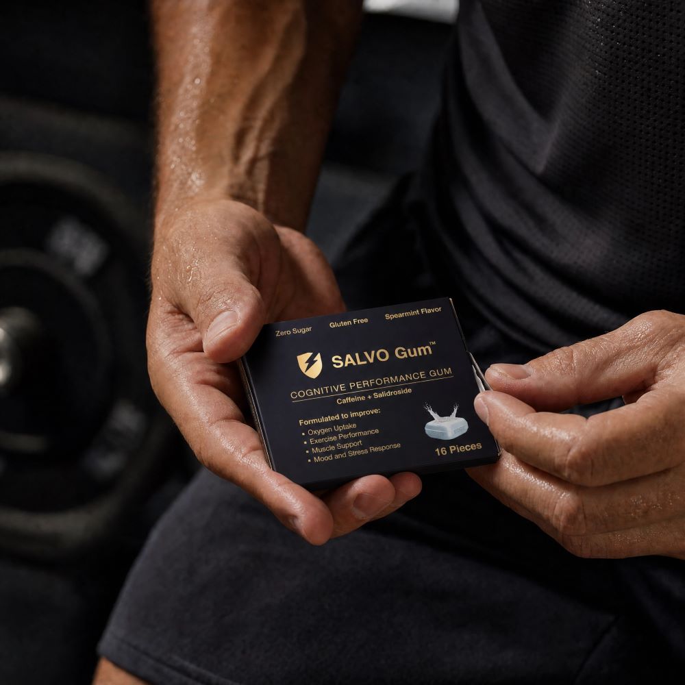 A person with sweaty arms holds a black package of Salvo Cognitive Performance Gum in a gym.
