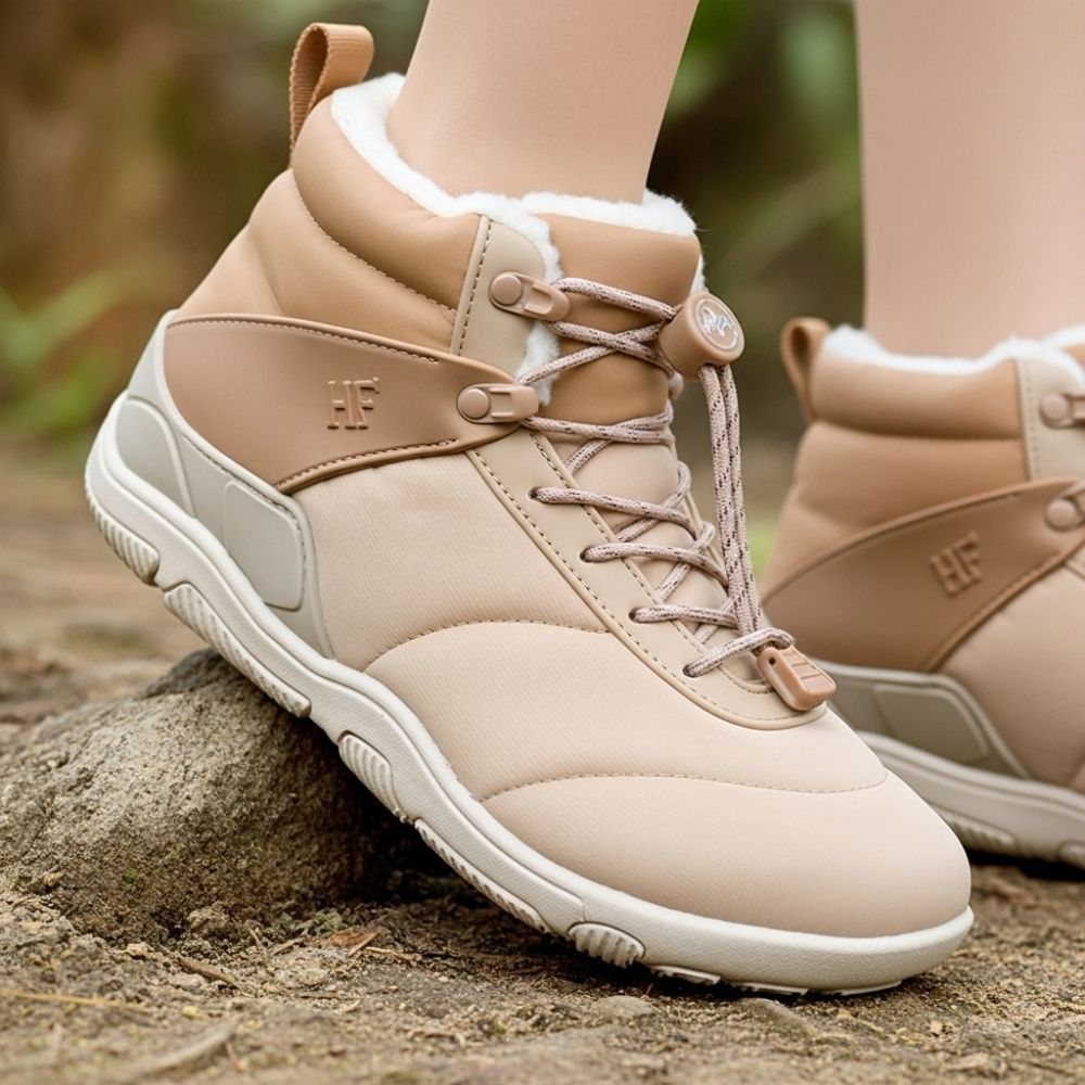 Tan winter boots with fluffy lining and lace-up design on outdoor path.