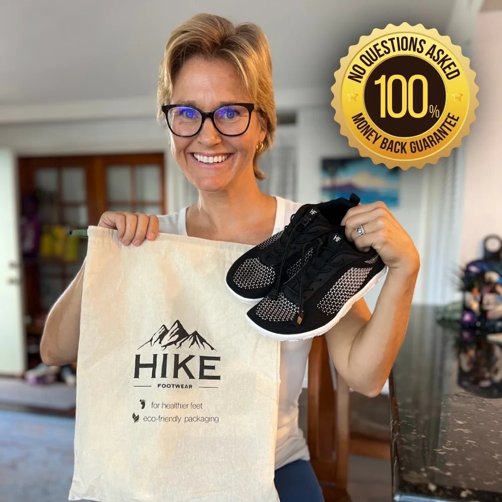 Person holding a pair of black sneakers and a Hike Footwear bag.