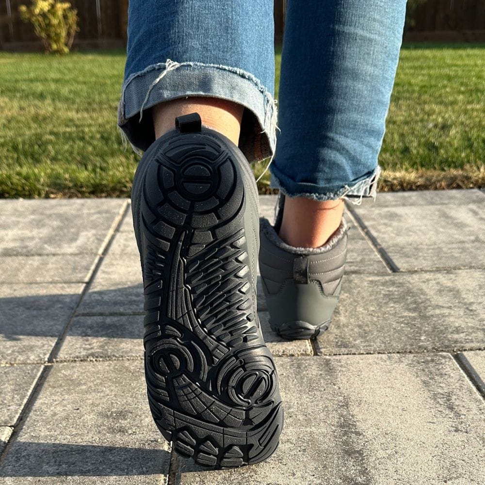 Close-up of a shoe sole on pavement, person wearing jeans.