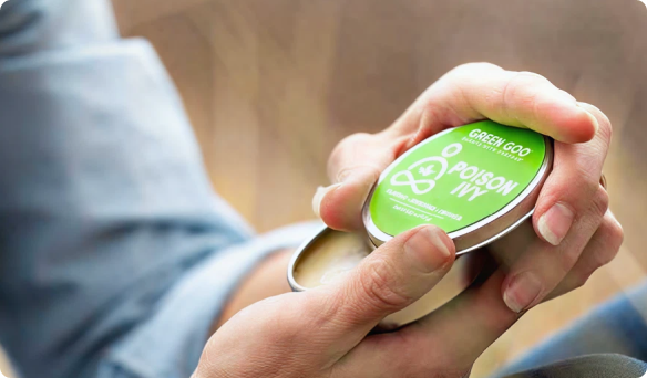 Hands holding a tin labeled 'Poison Ivy' with a green lid.
