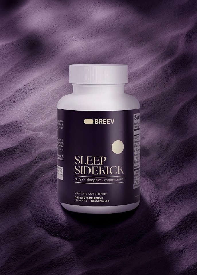 A person sleeps peacefully in a sunlit bed with a bottle of Sleep Sidekick supplements on the sheets.