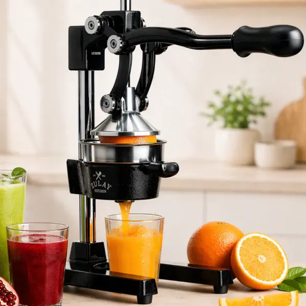 A black manual citrus press squeezing fresh juice from an orange into a glass on a kitchen counter.