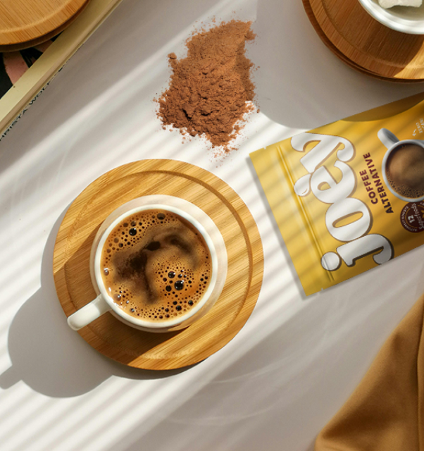 Cup of coffee on a wooden coaster with coffee alternative packet and powder.