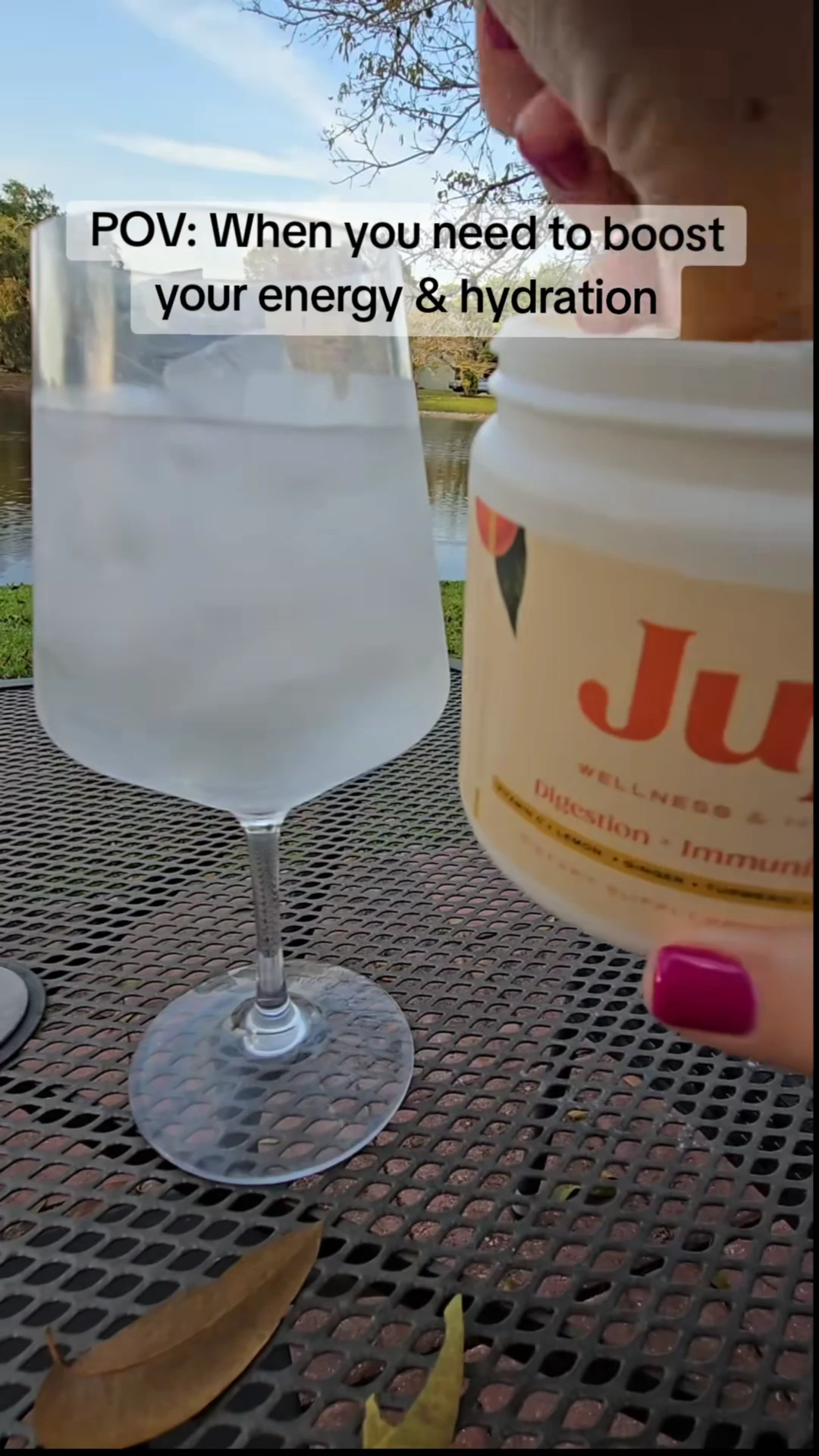 Glass of ice water and a container on a metal table outdoors.