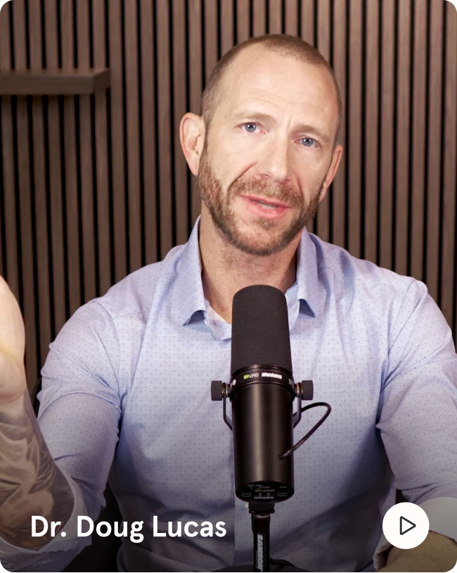 A man with a beard, Dr. Doug Lucas, speaks into a podcast microphone in front of a wood-paneled wall.