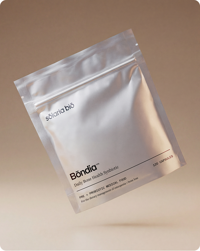 A silver, resealable pouch of Bōndia Daily Bone Health Synbiotic capsules on a light brown background.