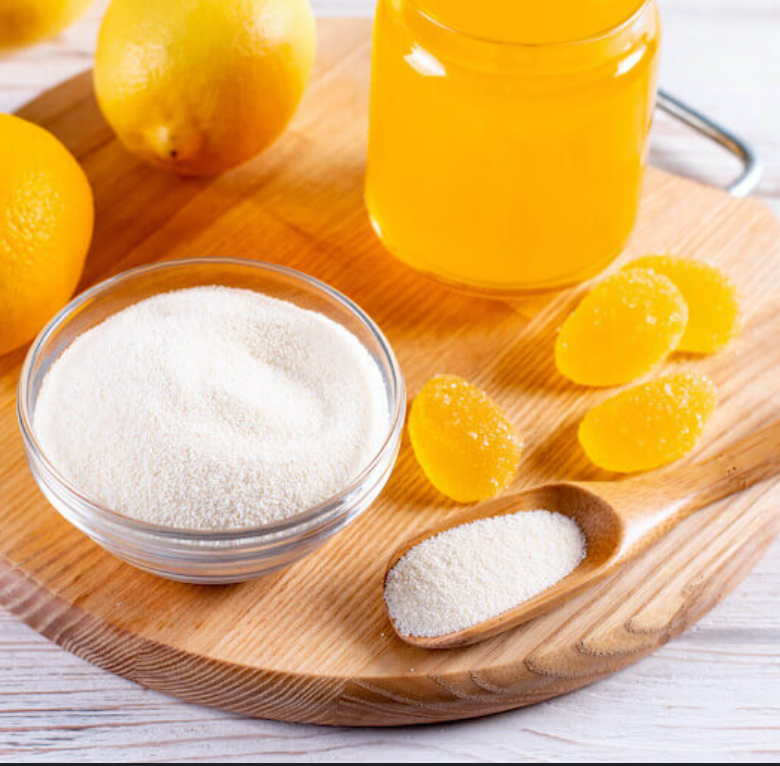 Lemons, jar of liquid, powder in glass bowl, and candies on wooden board.