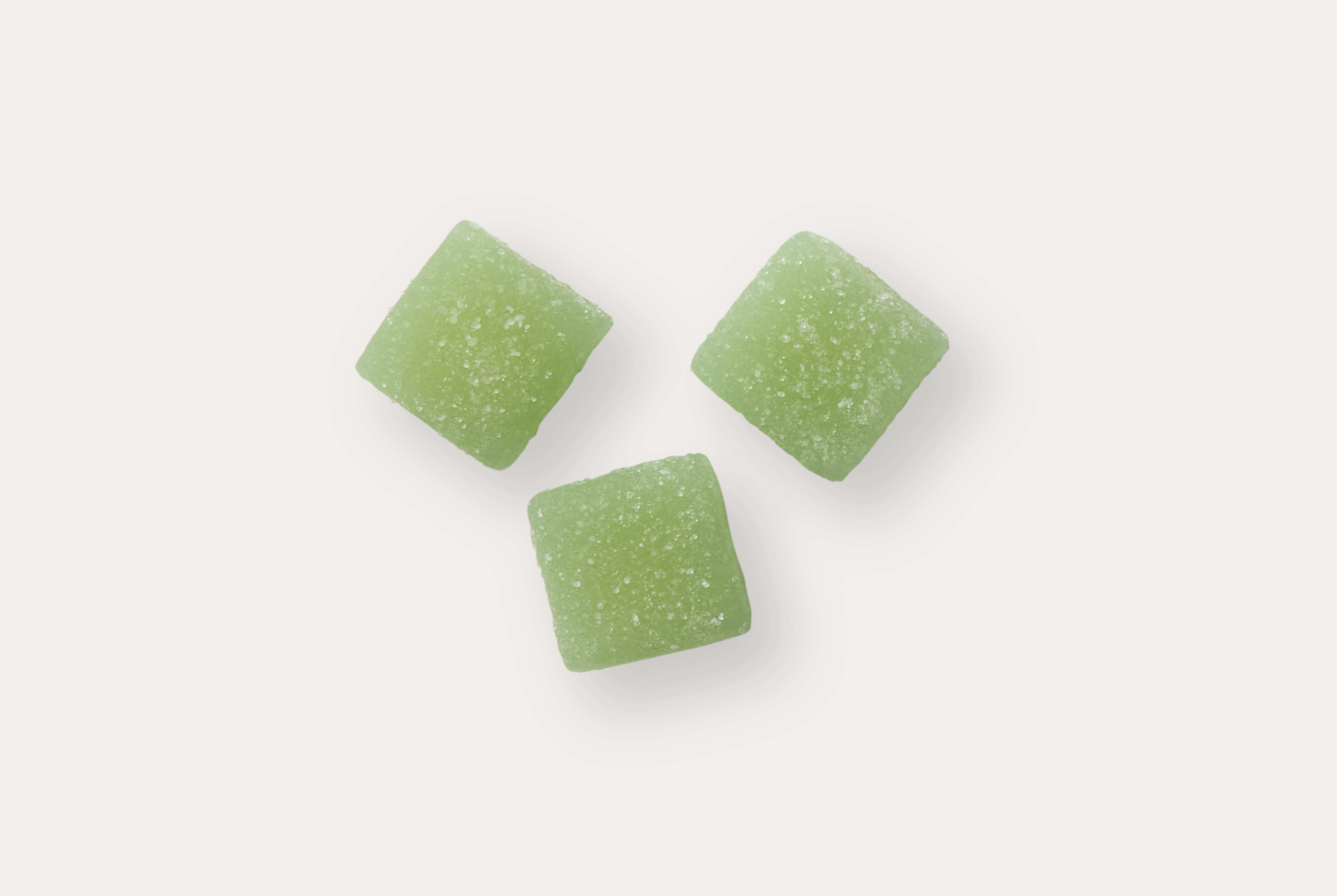 Three green sugar-coated gummy candies on a white background.