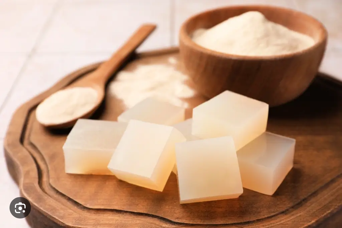 Blocks of translucent soap with a bowl and spoon of powder on a wooden tray.