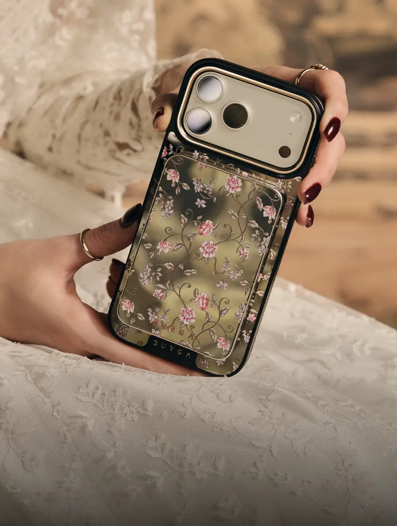 A person wearing a white lace dress holds a smartphone in a floral-patterned case.