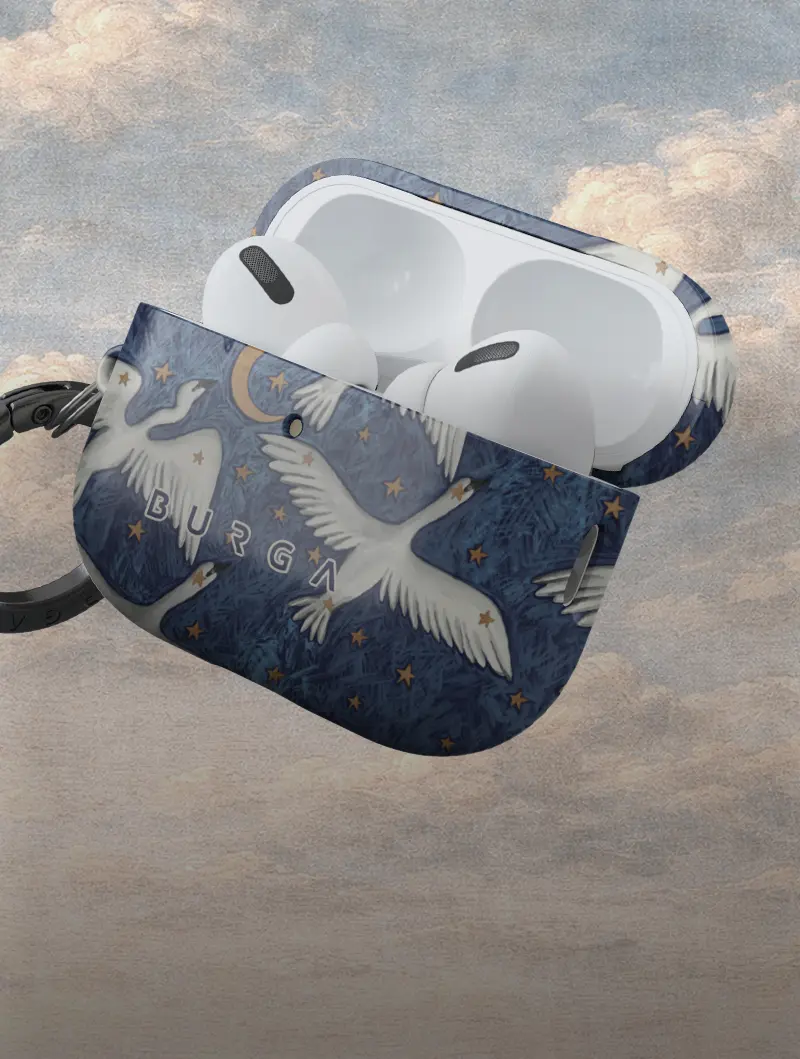 White wireless earbuds in an open blue case decorated with white swans, a moon, and gold stars.