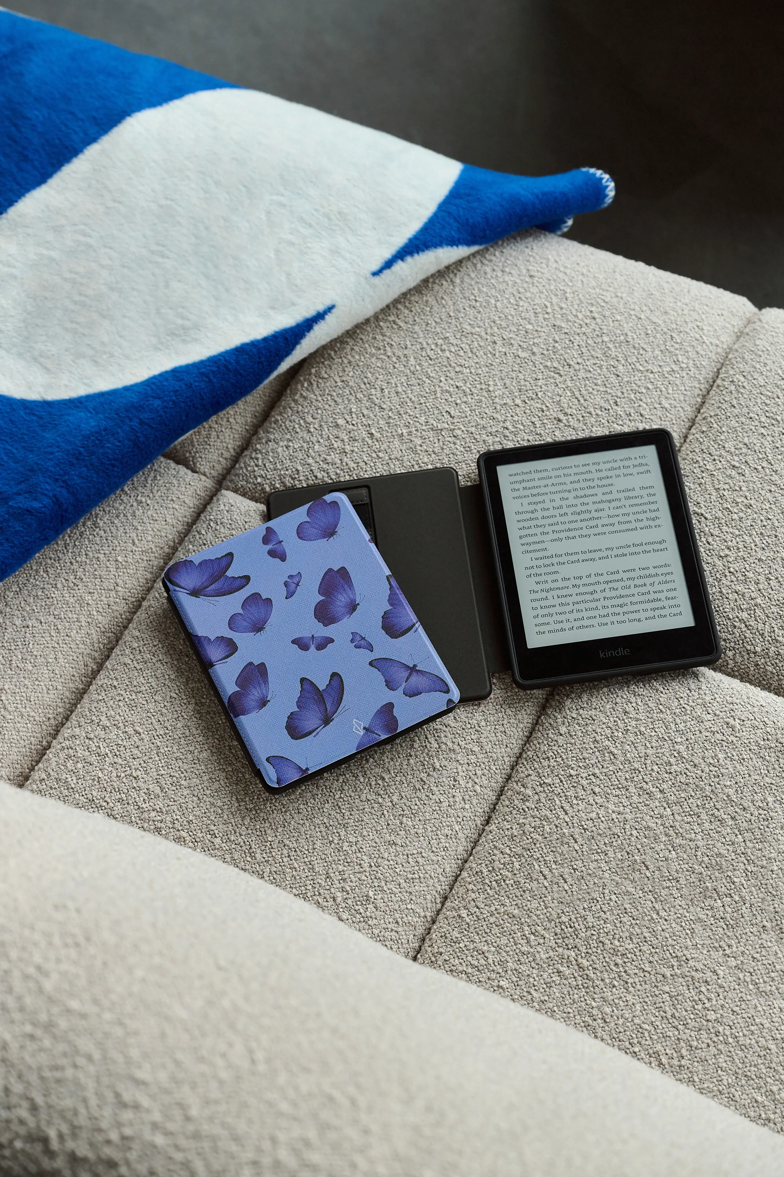 E-reader with butterfly cover on a beige couch.