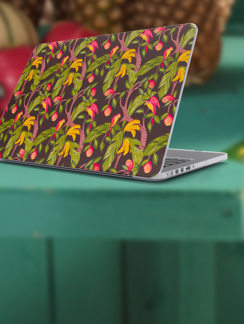 Laptop with colorful floral design on the cover, placed on a green table.