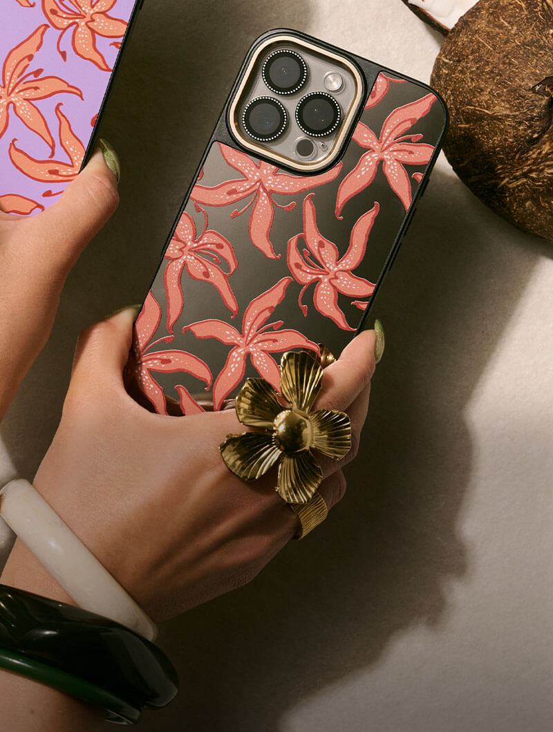 Hand holding a phone with floral case and large flower ring.