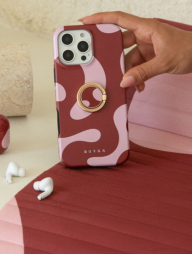 Hand holding a phone with a red and pink patterned case.