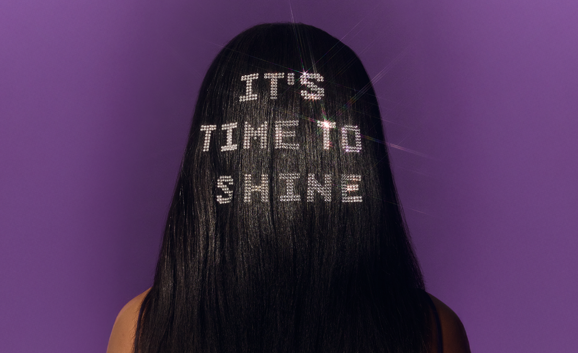 Back of woman's head with 'It's time to shine' in rhinestones on hair.