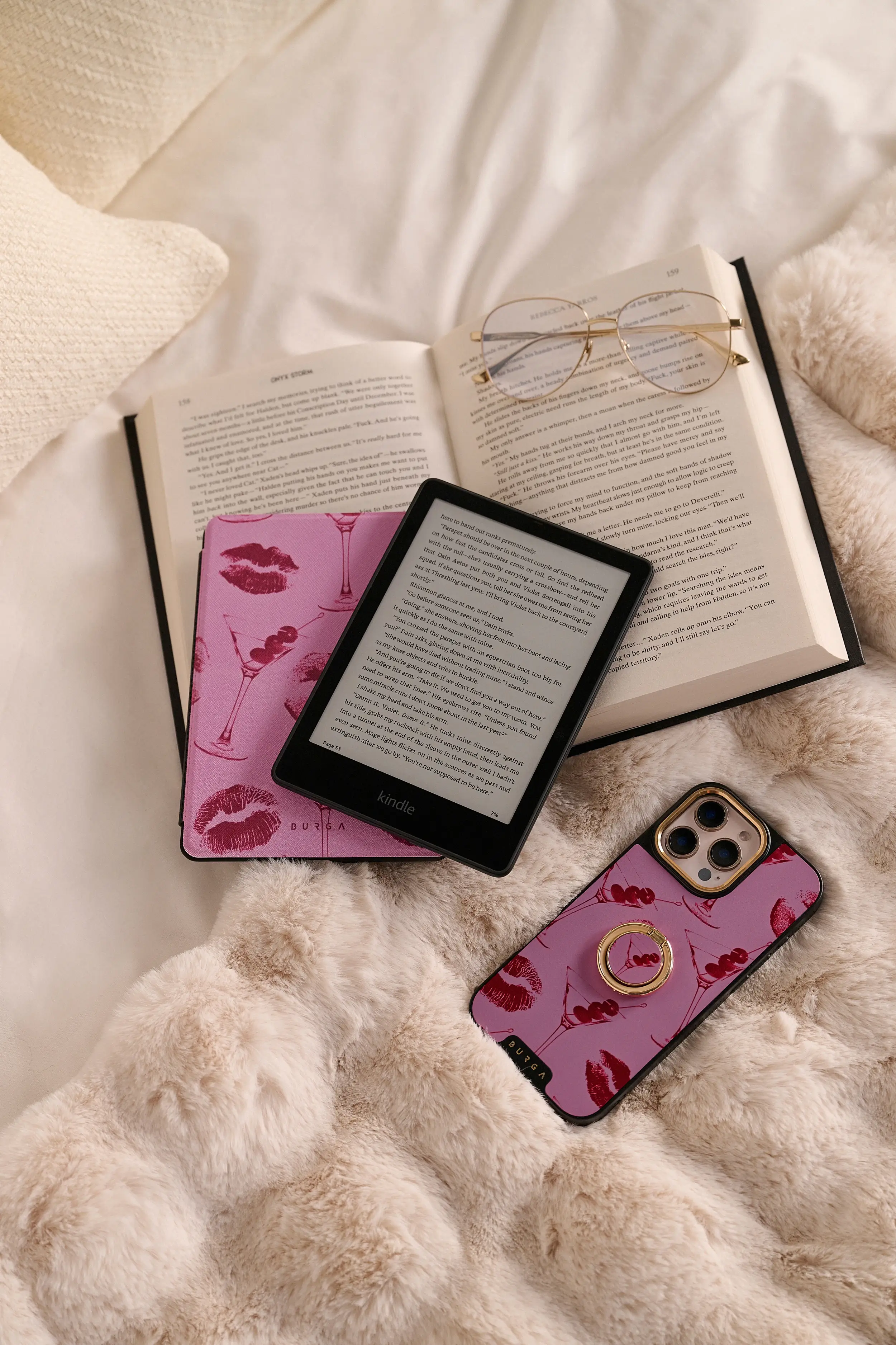 Open book, Kindle, glasses, and phone on a fluffy blanket.