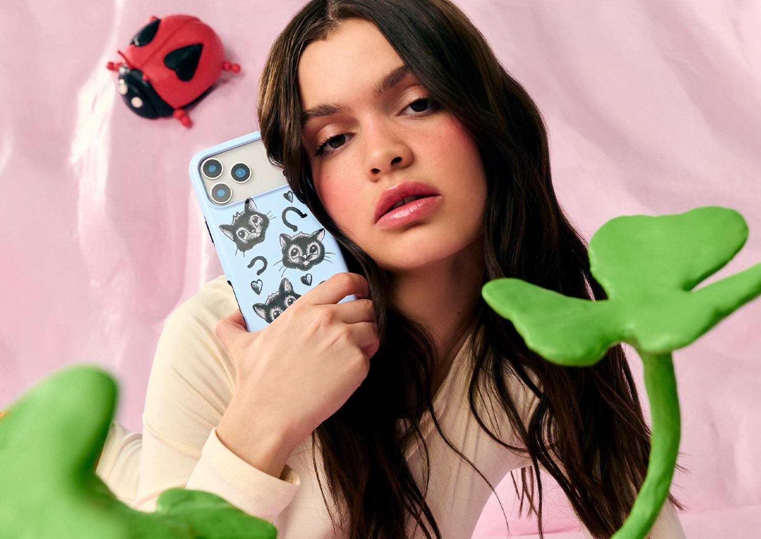 Three patterned phone cases on a silver platter with wax-sealed letters and a heart locket.