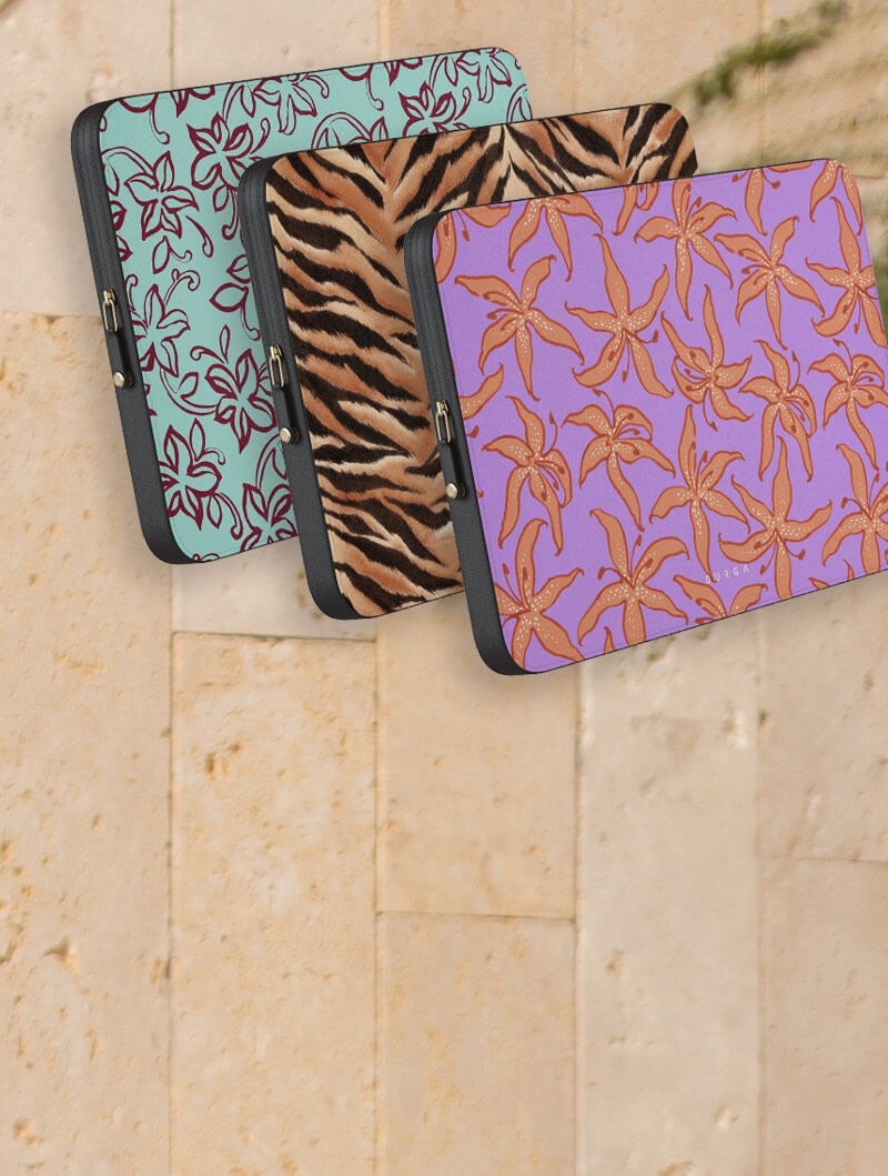 Three patterned laptop sleeves against a stone wall background.