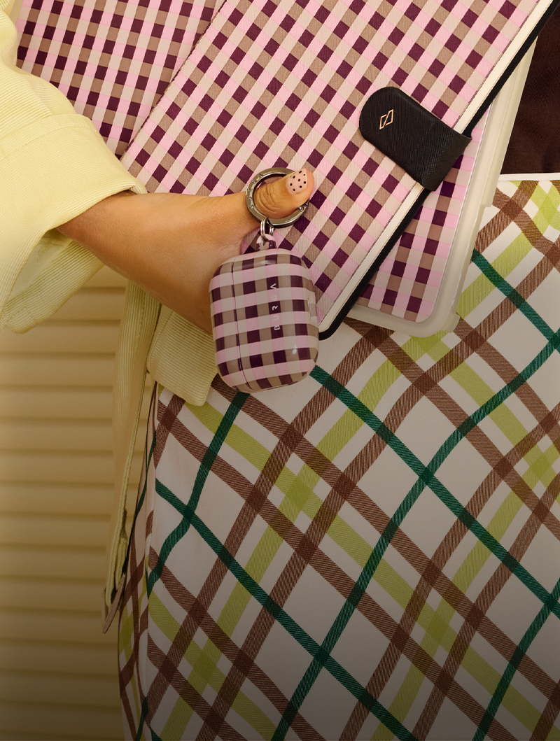 A hand holding patterned items with checkered designs in pink, purple, green, and brown.