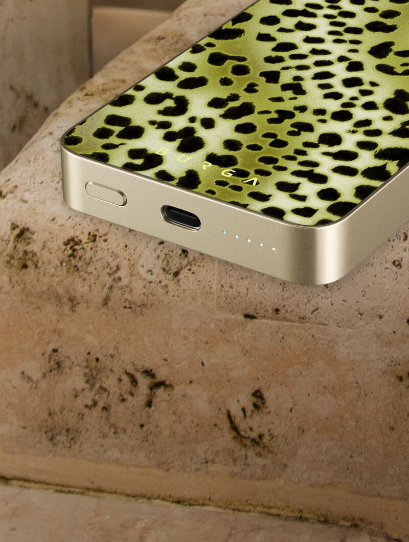 Smartphone with green leopard print case on stone surface.