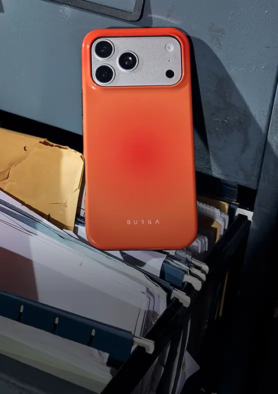 A smartphone in a bright orange Burga case resting on top of an open file cabinet drawer.