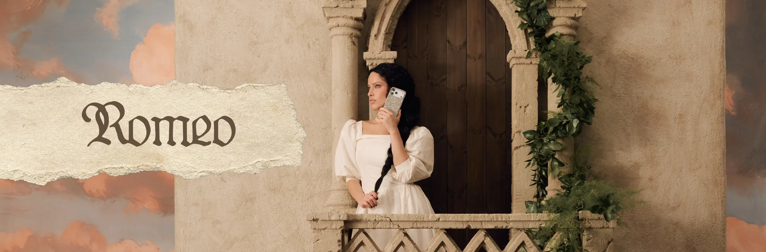 A woman in a white period dress stands on a stone balcony holding a smartphone.