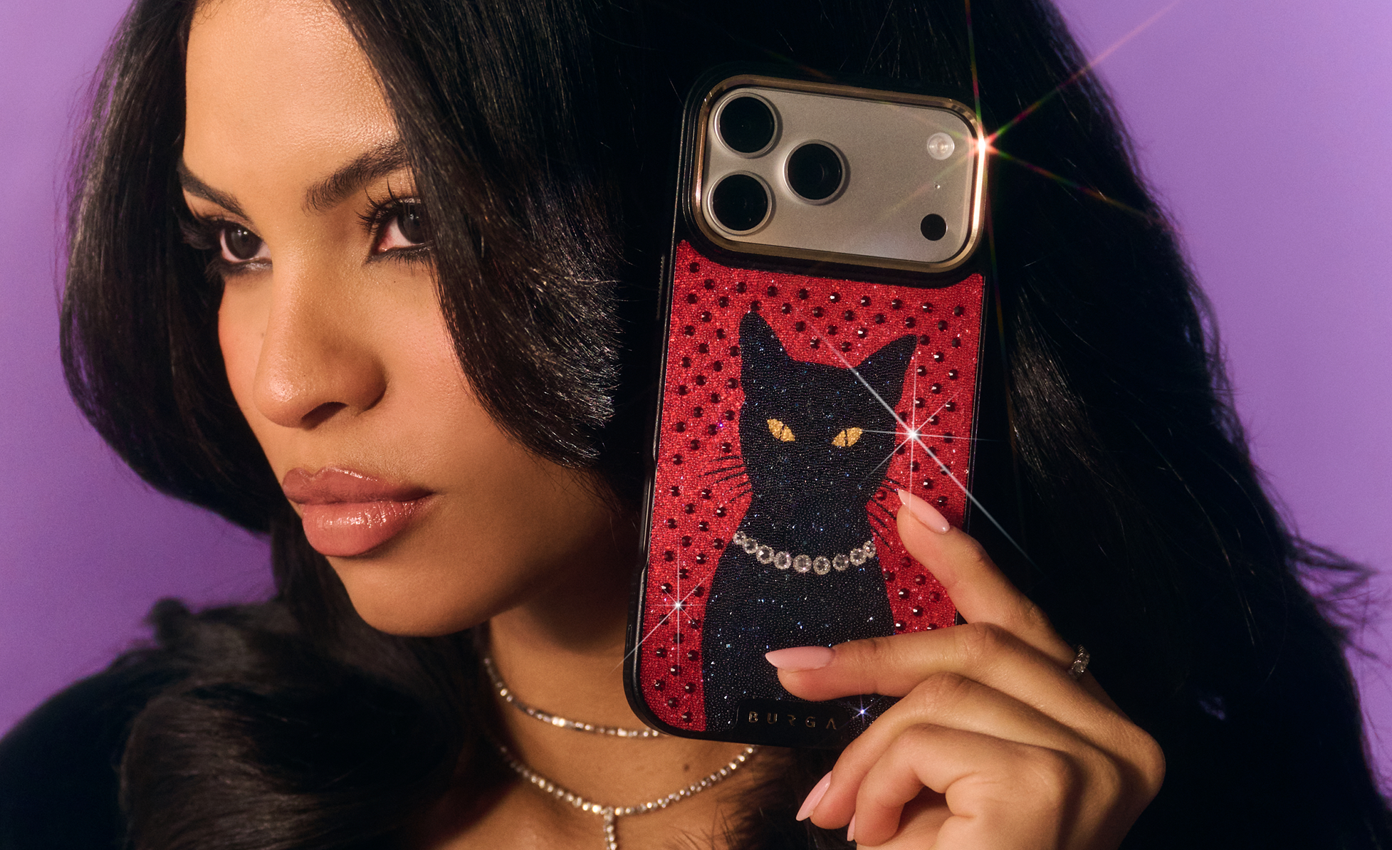 Woman holding phone case with black cat design against purple background.