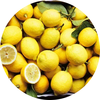A circular photo shows a pile of whole and cut fresh lemons with some green leaves.