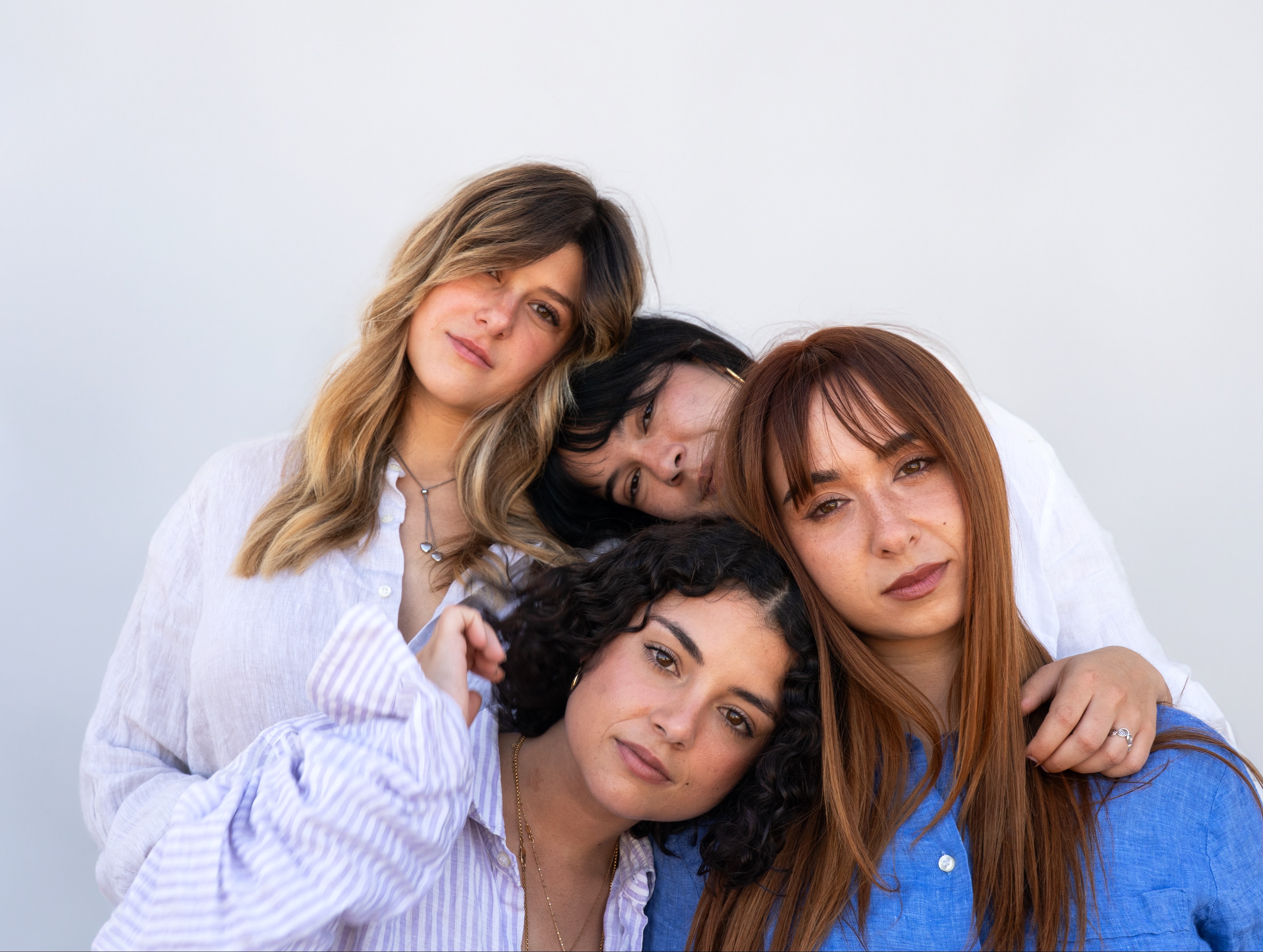 Quattro donne con diversi tipi di capelli, che posano vicine e affettuosamente, simboleggiando la versatilità delle formule Originae. I loro capelli sani e naturali riflettono l'efficacia dei prodotti naturali, senza sostanze aggressive, ideali anche per capelli secchi o trattati.