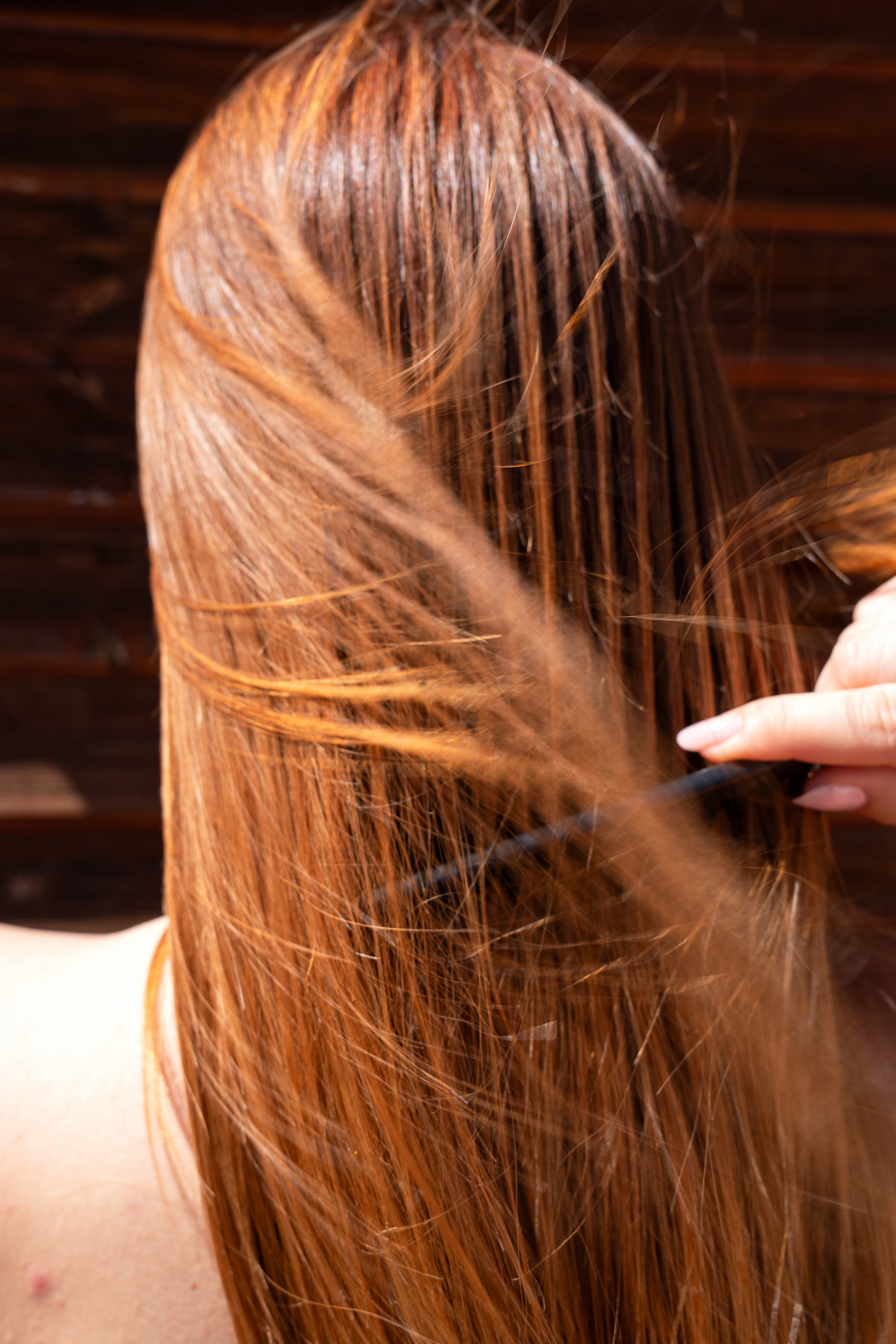 Dettaglio di lunghi capelli lisci e lucenti di un tono castano-dorato, che vengono pettinati delicatamente. L'immagine rappresenta una cura quotidiana per capelli sani e nutriti, grazie alle formule Originae con ingredienti naturali e senza sostanze chimiche aggressive.