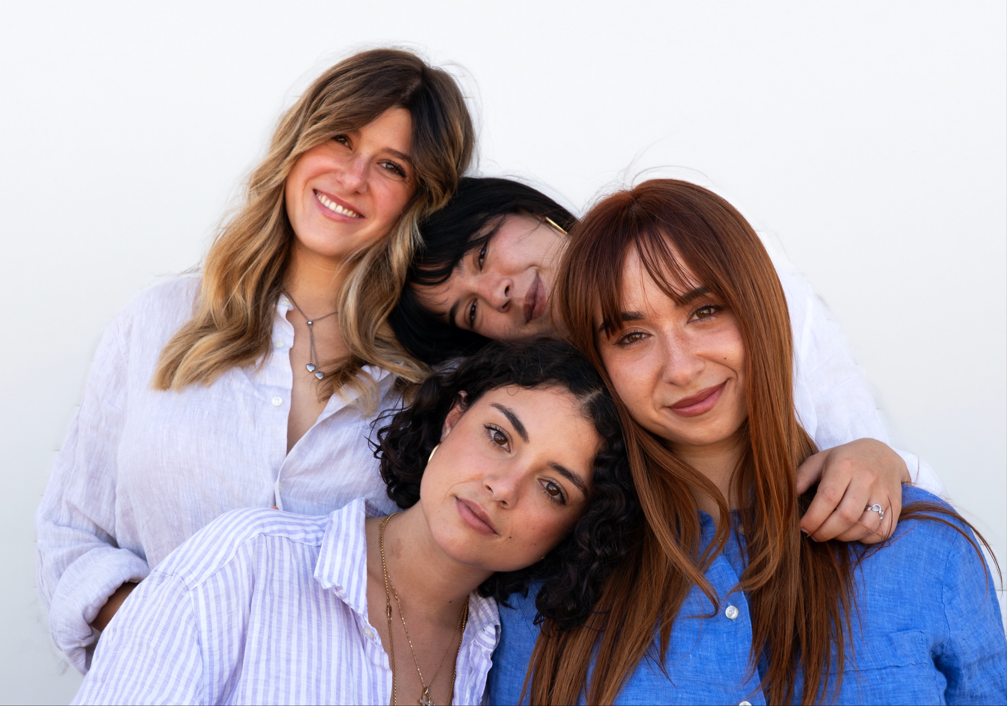 Quattro amiche con capelli sani e naturali, che posano insieme in modo affettuoso, riflettendo l'efficacia delle formule delicate Originae, adatte a ogni tipo di capello e prive di sostanze chimiche aggressive.