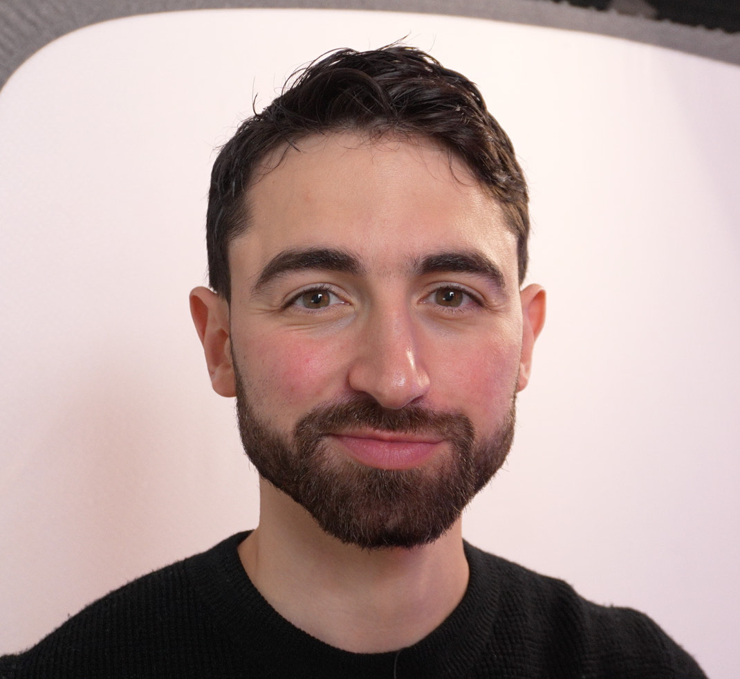 A man with dark hair and a beard smiling at the camera.