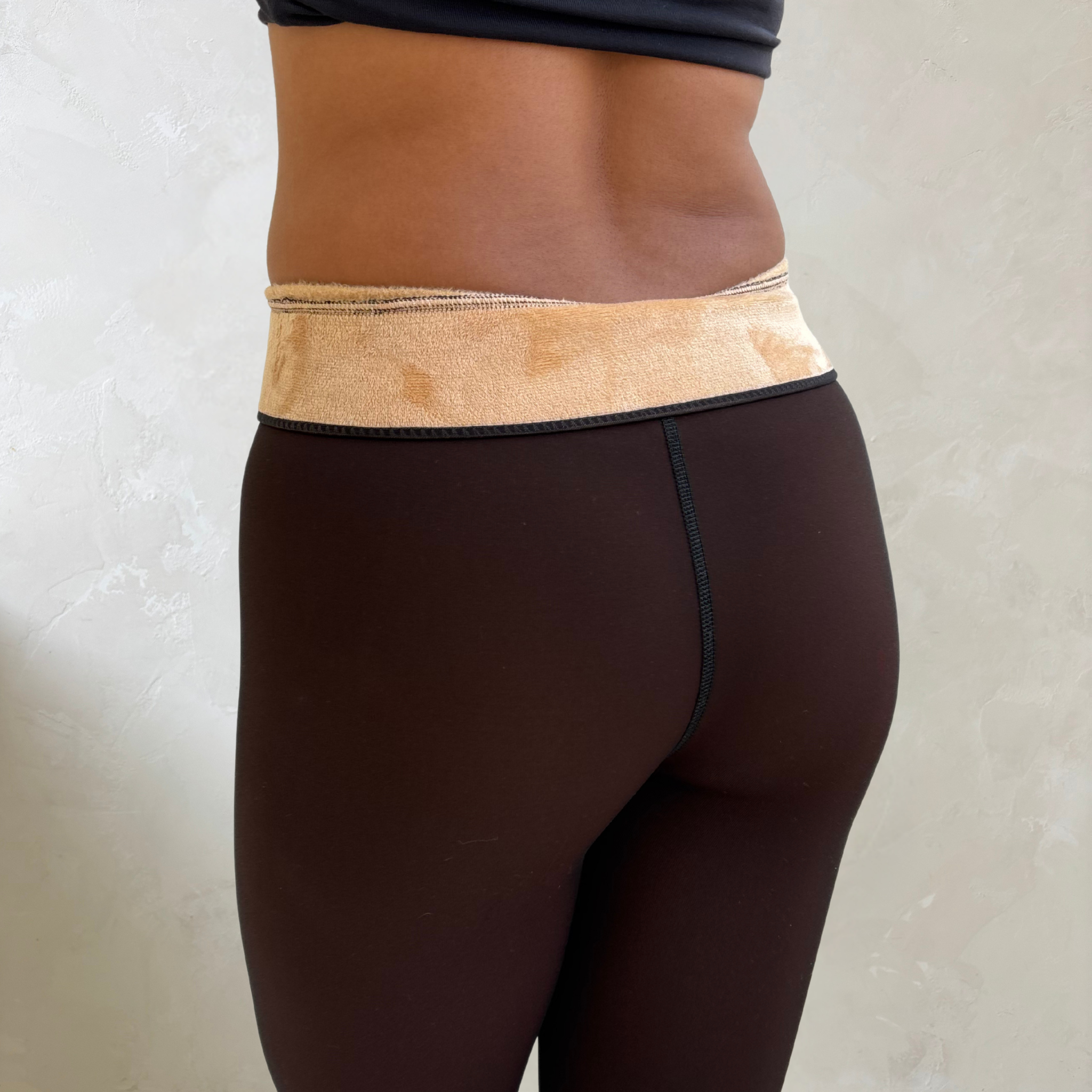 Close-up of a person's lower back wearing black leggings and beige waistband.