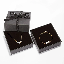 Gold necklace and bracelet with pearls in black gift boxes.
