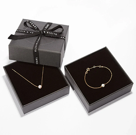 Gold necklace and bracelet with pearls in black gift boxes.